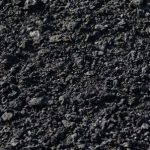 The background is the texture of small black fragmented stones in the form of asphalt crumbs A lot of building material for industrial repair of black coal roads High quality photo